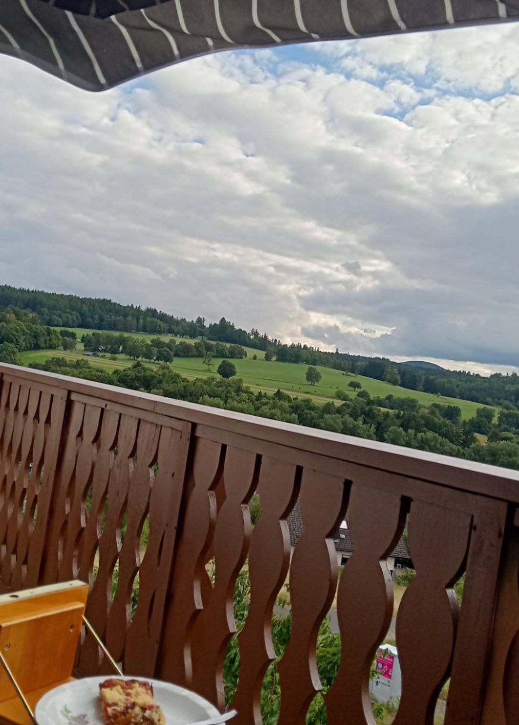 Blick auf grüne Hügel und Wolkenhimmel von einer Terrasse aus.